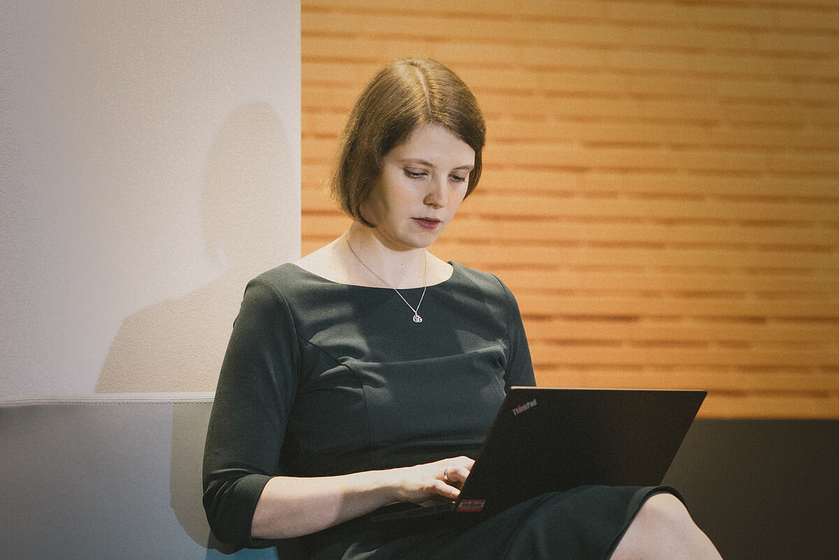 Dr. Anica Graf sitzend mit einem Laptop auf dem Schoß.