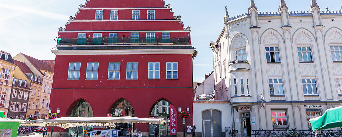 Rathaus Greifswald am Marktplatz Das rote Rathaus der Universität Greifswald mit dem Marktplatz vor einem sonnigen Himmel.