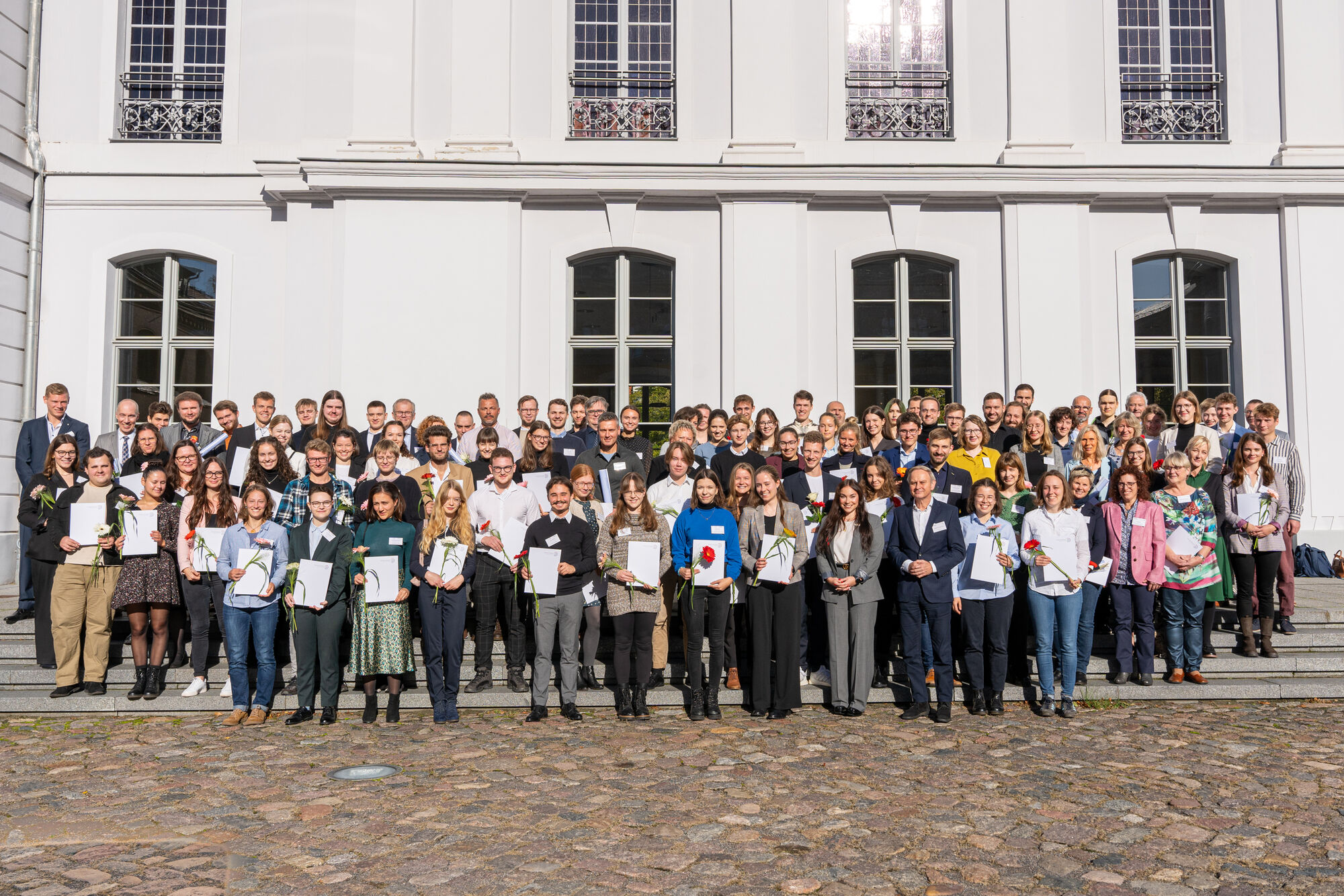 Group photo after the Deutschlandstipendium award ceremony 2023. The scholarship holders alonside their donors in front of the university's Main Building.