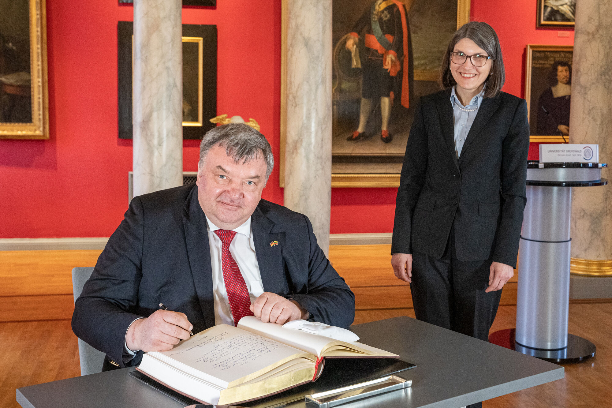 The Ambassador of Lithuania signing the university's guest book in the university's Aula.