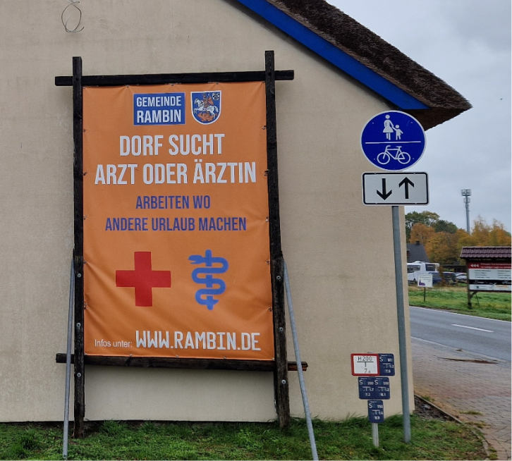 Ein Plakat vor einem Haus wirbt um Ärzte