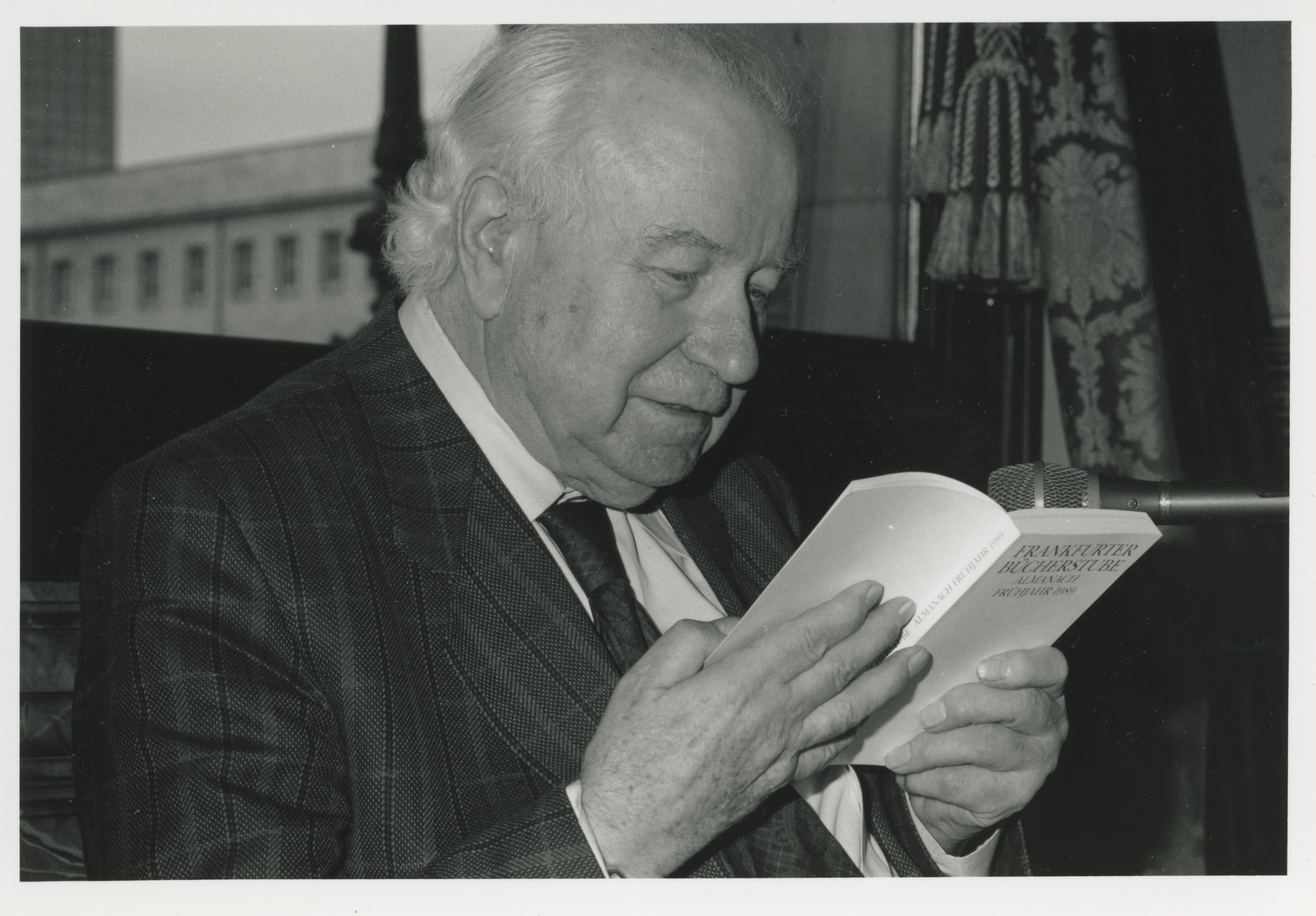 Schwarzweiß-Porträt von Wolfgang Koeppen. Er liest in einem Buch.