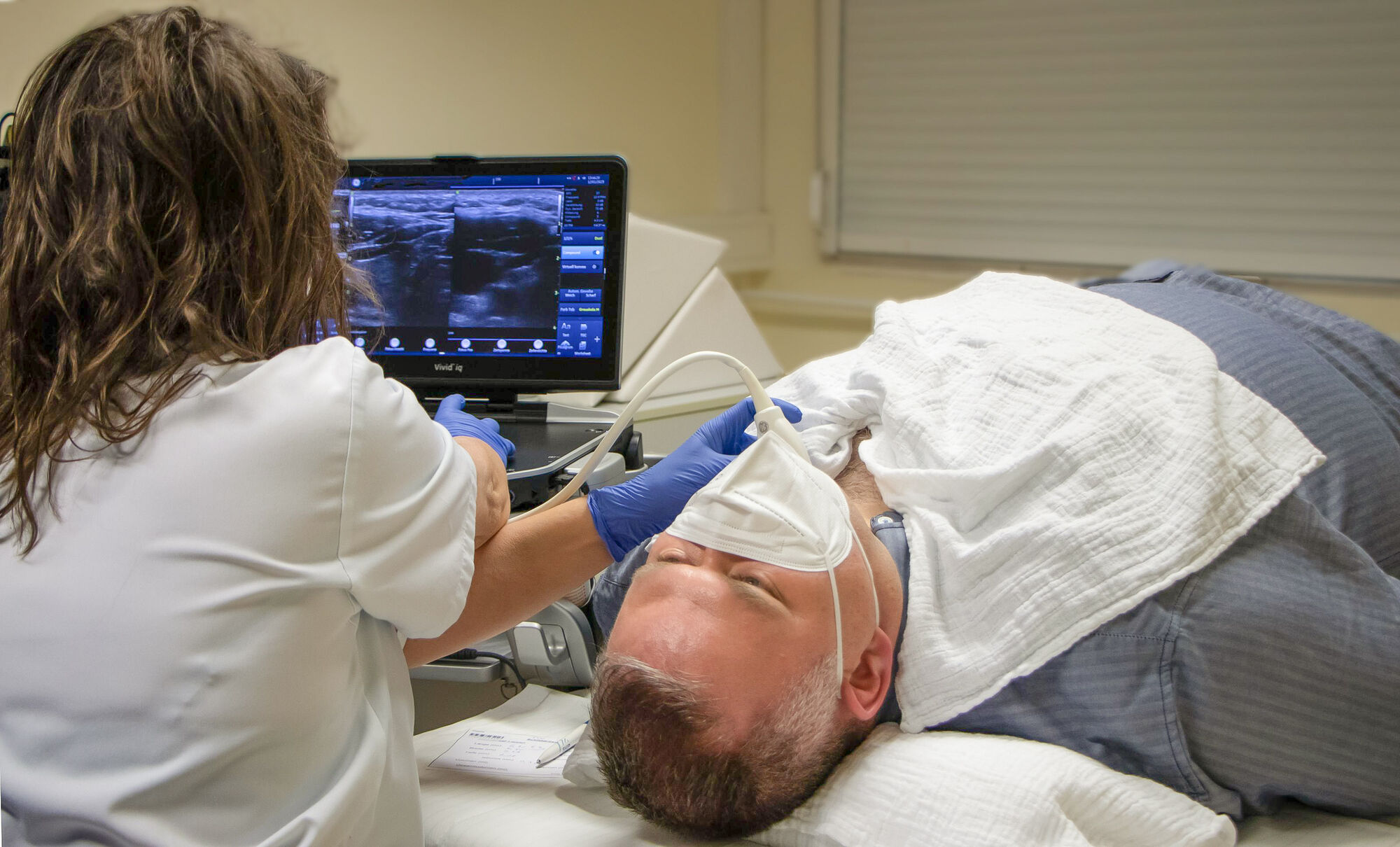 Eine Untersucherin nimmt einen Ultraschall von der Schilddrüse vor.