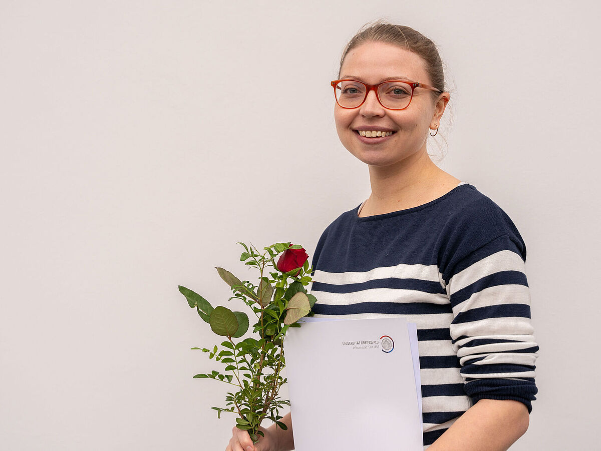Alisa Otte mit Blumenstrauß und Zertifikat über den Preis.