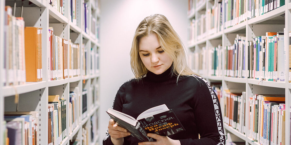 Auf dem Foto sieht man eine junge Studentin, welche ein Buch zur russischen Sprache liest. 
