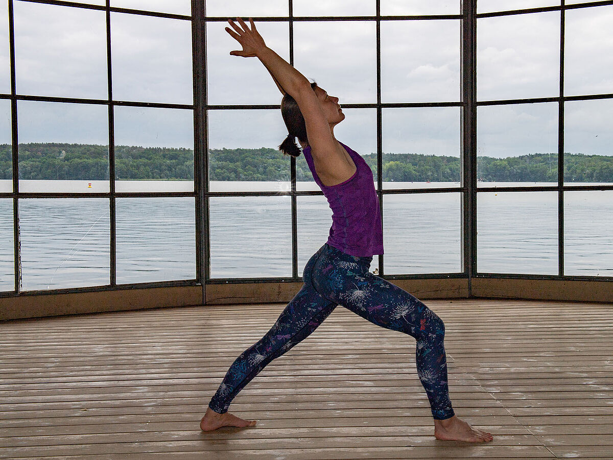 Auf dem Bild ist eine Person zu sehen, die Yoga auf einer Yogamatte macht.