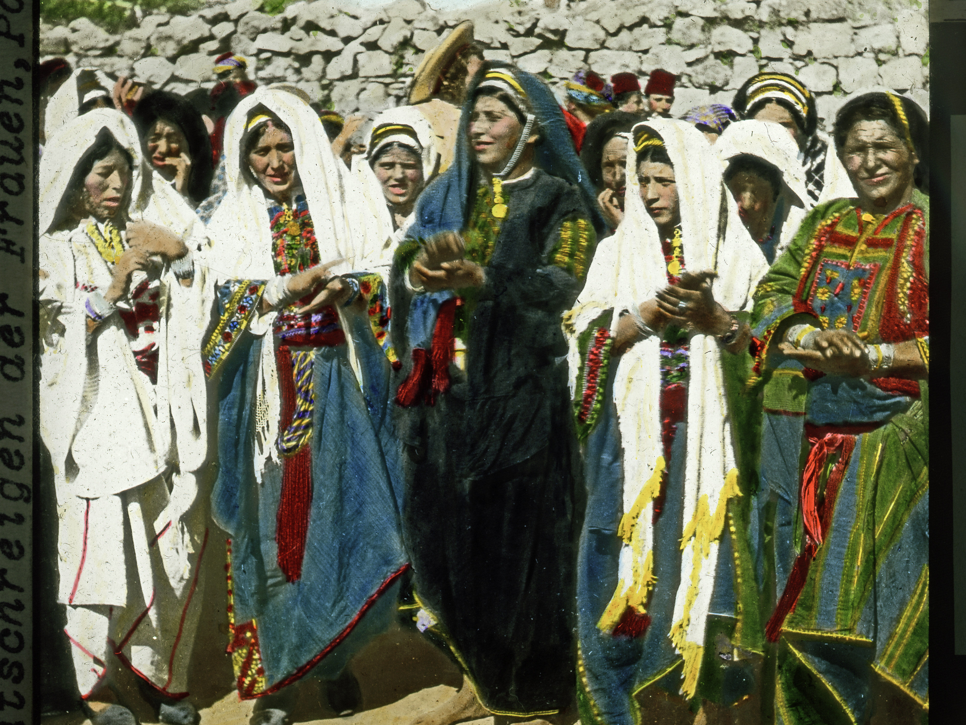 Gustaf Dalman: Klatschreigen der Frauen bei einer Hochzeit in Ramallah, vor 1914 – einmal als Original-Schwarz-Weiß-Fotografie aus der Zeit vor dem Ersten Weltkrieg, einmal als handkoloriertes Glasplattendia, wie es der Hentschel-Verlag vor dem Zweiten Weltkrieg in sein Programm aufgenommen hatte (Foto: Gustaf Dalman, koloriertes Dia: Hentschel-Kunstverlag, Bild: Dalman-Institut als Scan vom Original-Negativ)