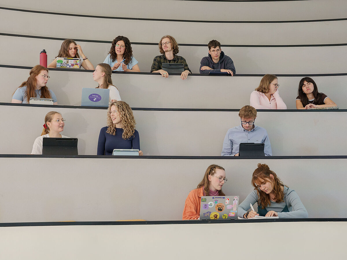 Studierende sitzen in einem Hörsaal und unterhalten sich.