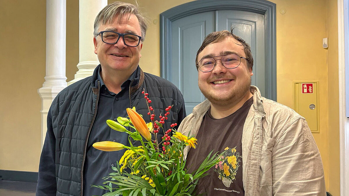 Zwei Männe, einer hält Blumen