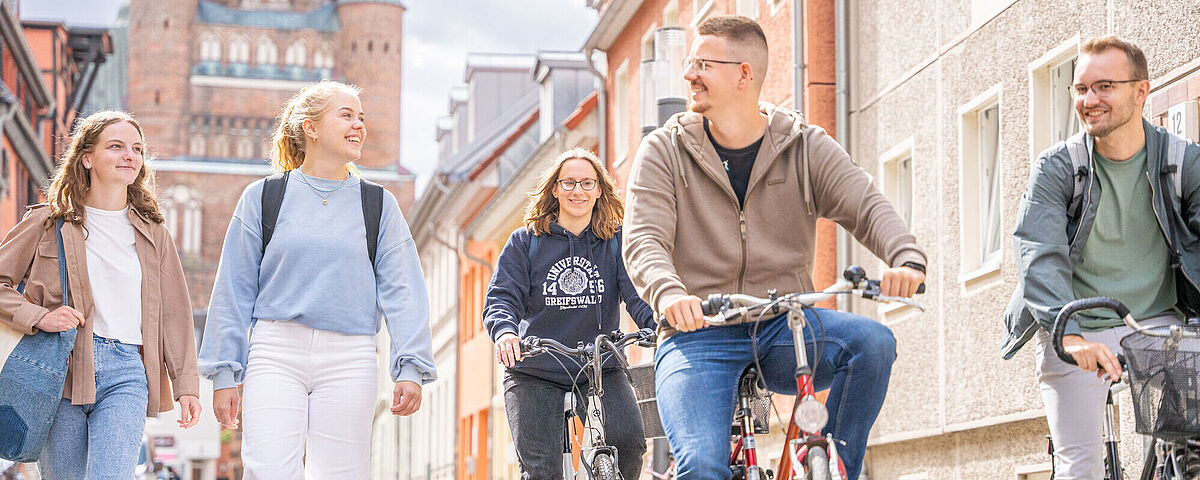 Auf dem Foto sind Studierende in der Stadt zu Fuß und mit dem Rad zu sehen.