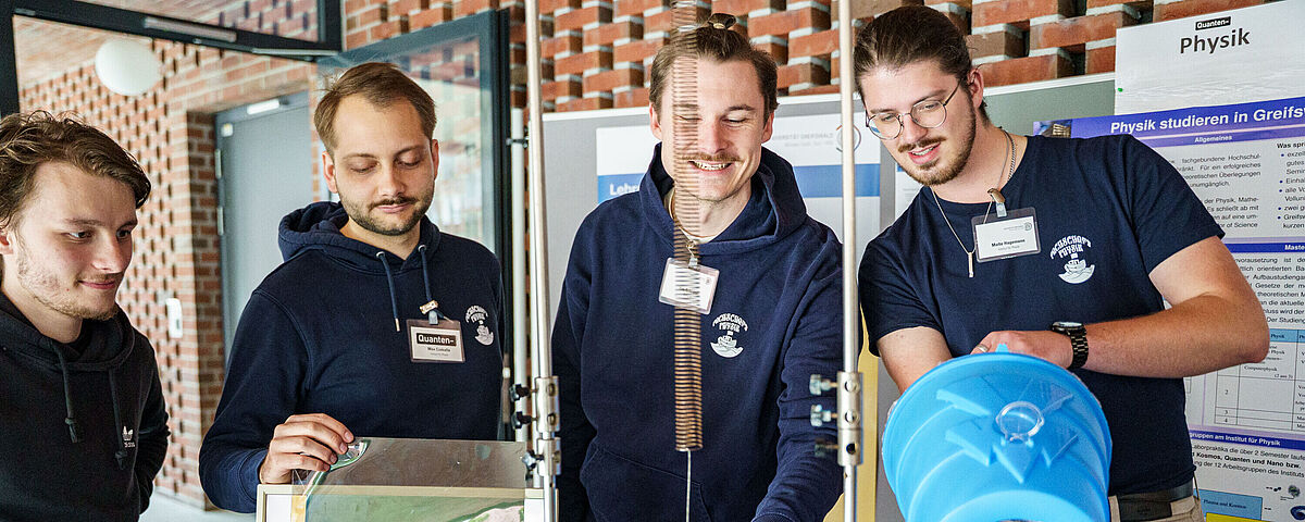 4 Physikstudenten zeigen stellvertretend für die Fachrichtung Physik Experimente.