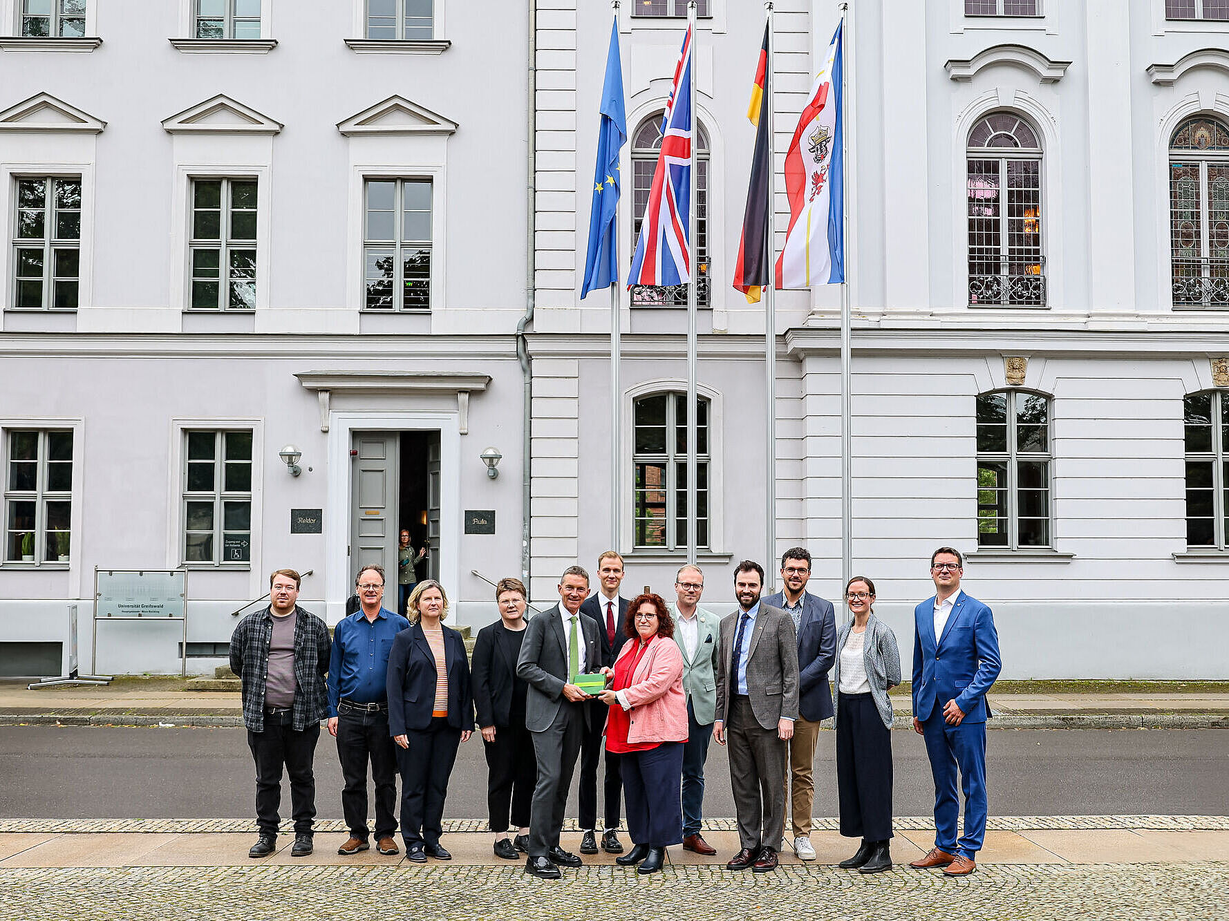 Ein Gruppenfoto vor dem Unihauptgebäude mit dem britischer Botschafter Andrew Mitchell CMG.