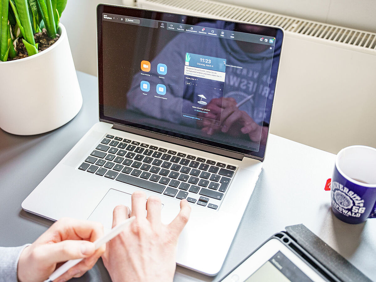 Eine Person sitzt vor einem geöffneten Laptop in einem Zoom-Meeting.