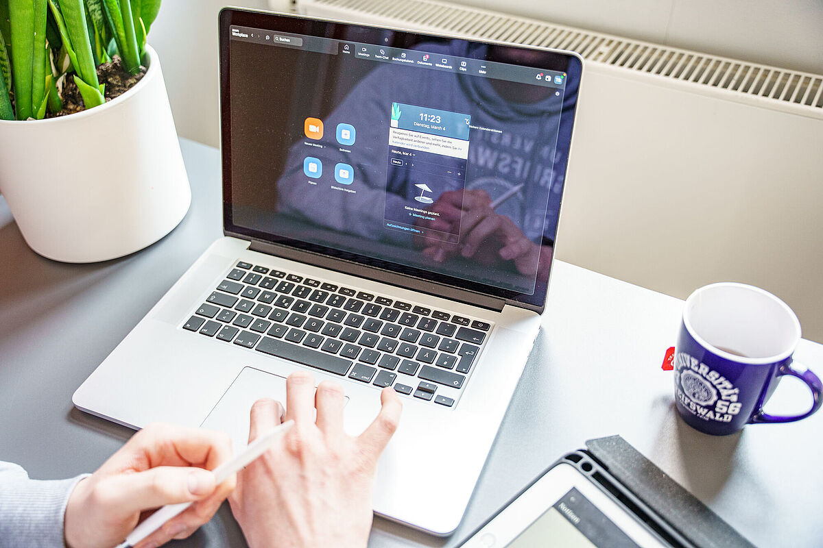 Eine Person sitzt vor einem geöffneten Laptop in einem Zoom-Meeting.