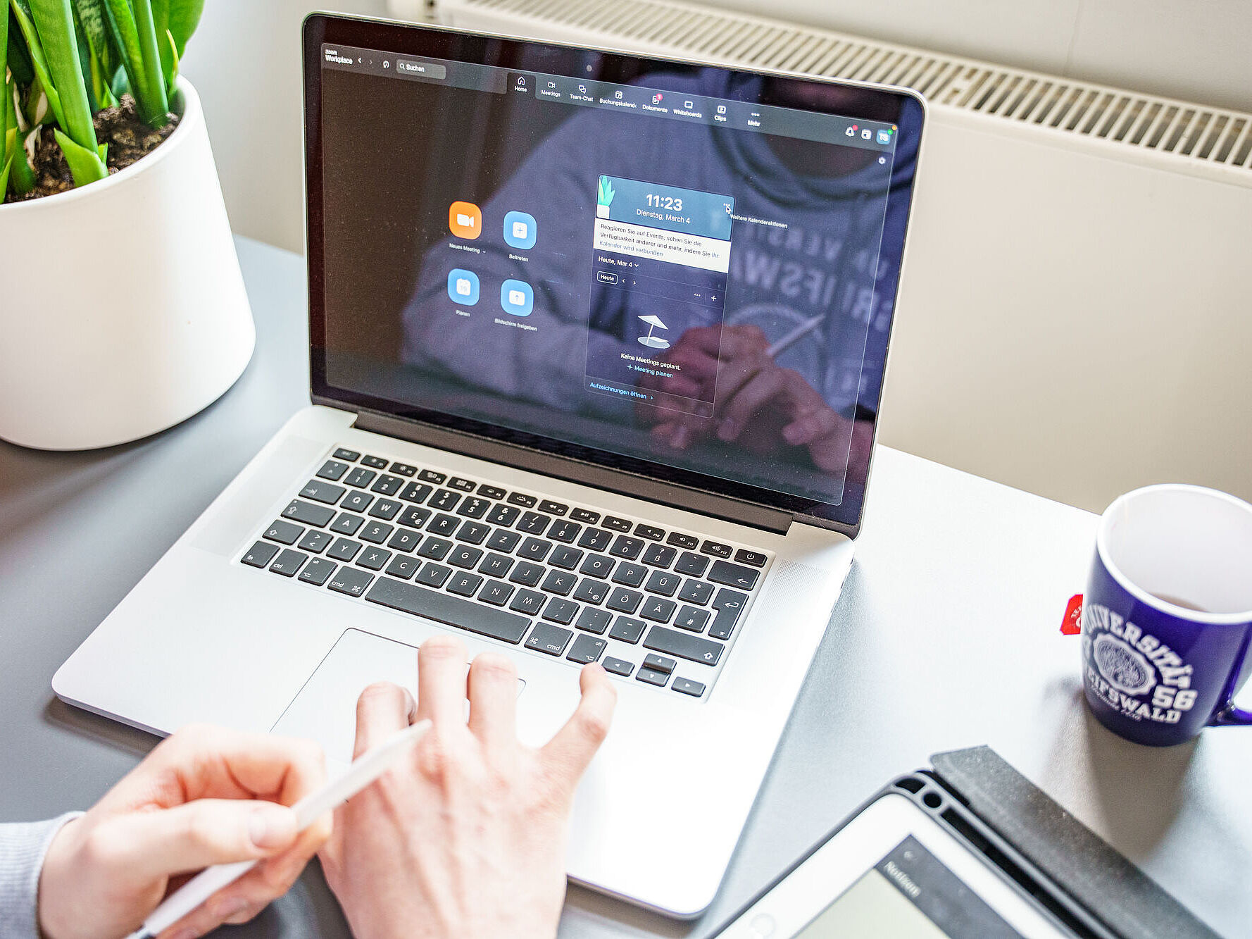 Symbolbild Online-Sitzung Zoom Eine Person sitzt vor einem geöffneten Laptop in einem Zoom-Meeting.