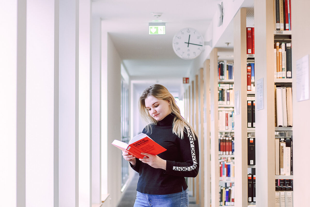 Auf dem Foto sieht man eine junge Studentin, welche ein Buch zur russischen Sprache liest. 