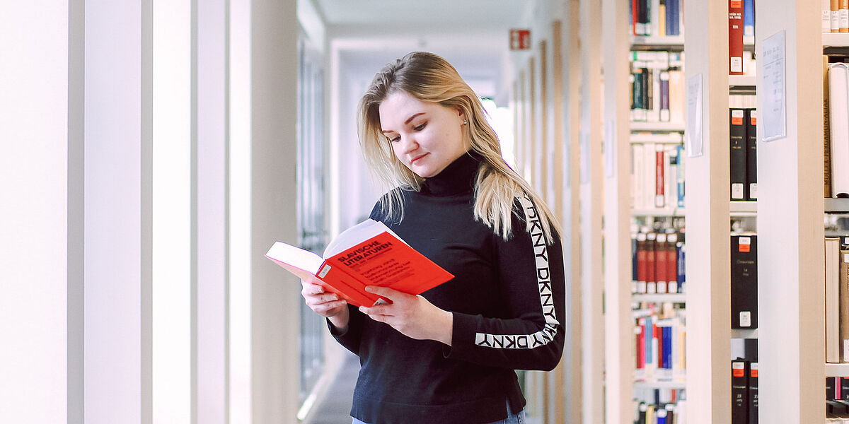 Auf dem Foto sieht man eine junge Studentin, welche ein Buch zur russischen Sprache liest. 