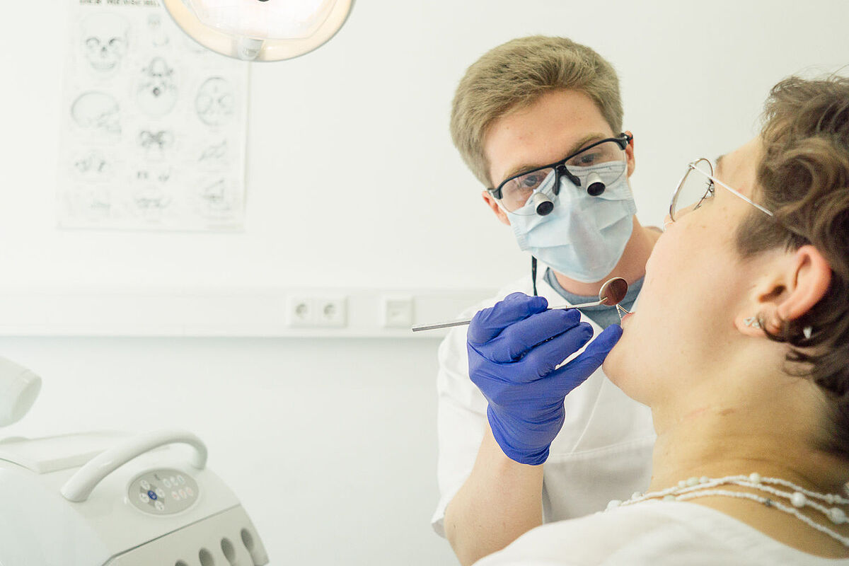 Eine Zahnärztin schaut einer Patientin in den Mund.