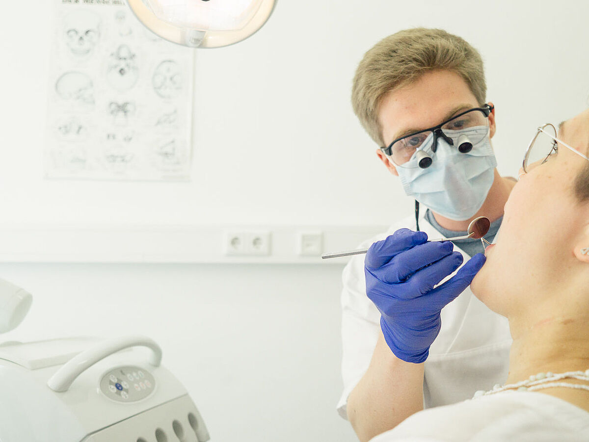 Eine Zahnärztin schaut einer Patientin in den Mund.