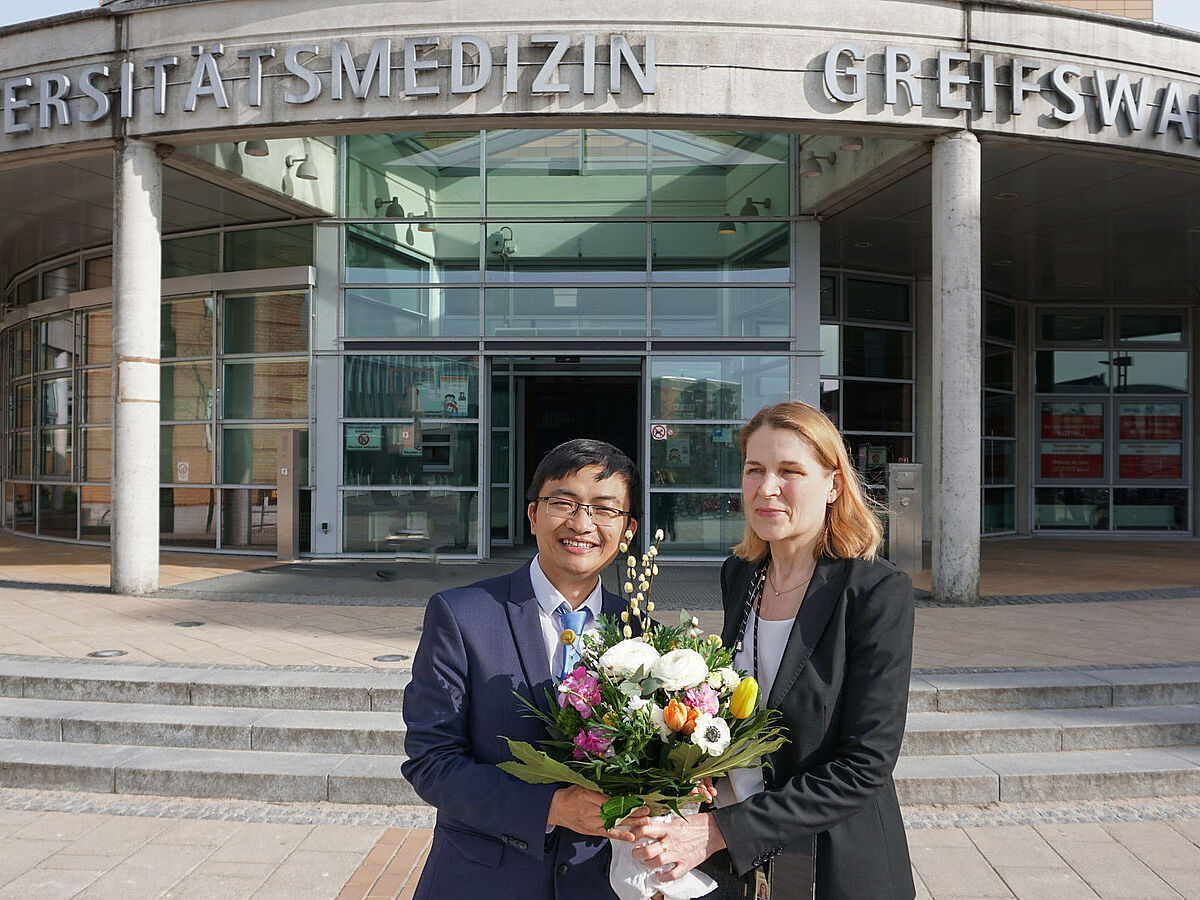 Quang Trung Tran und Prof. Dr. Elke Krüger vor dem Haupteingang der Universitätsmedizin.