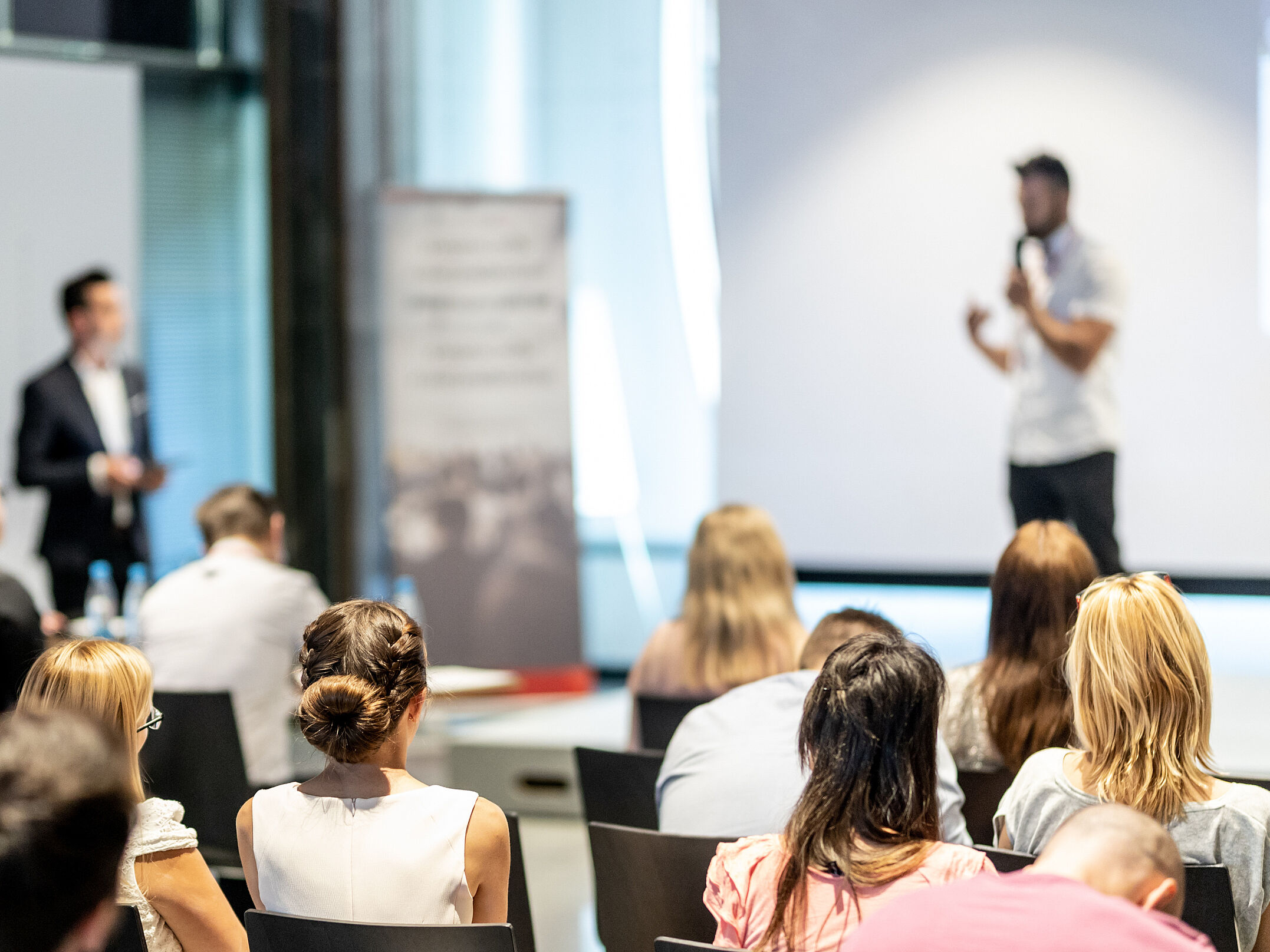 Das Publikum im Saal hört einem Redner zu.
