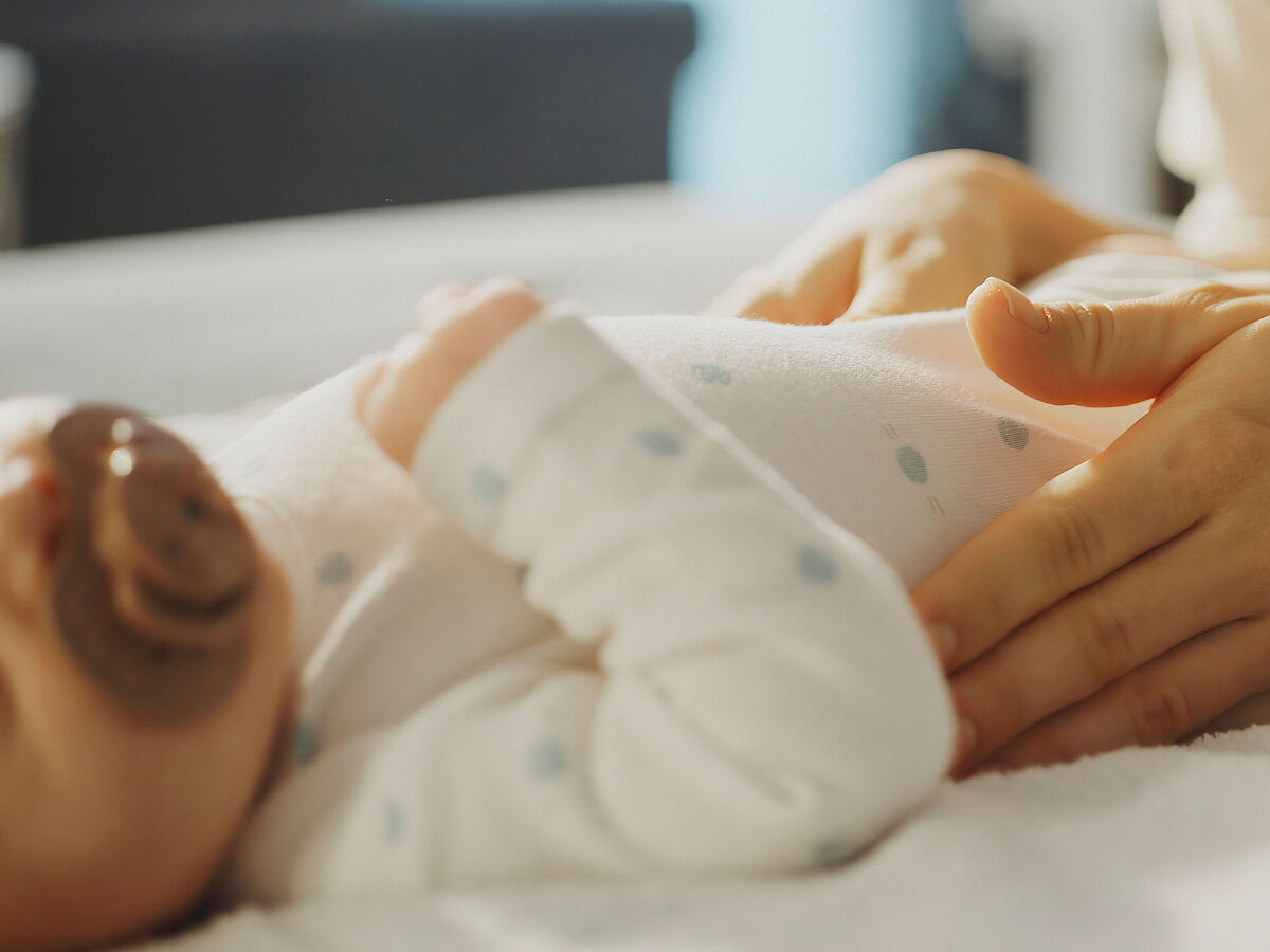 Auf einem Wickeltisch streichelt eine Mutter ihr kleines Baby.