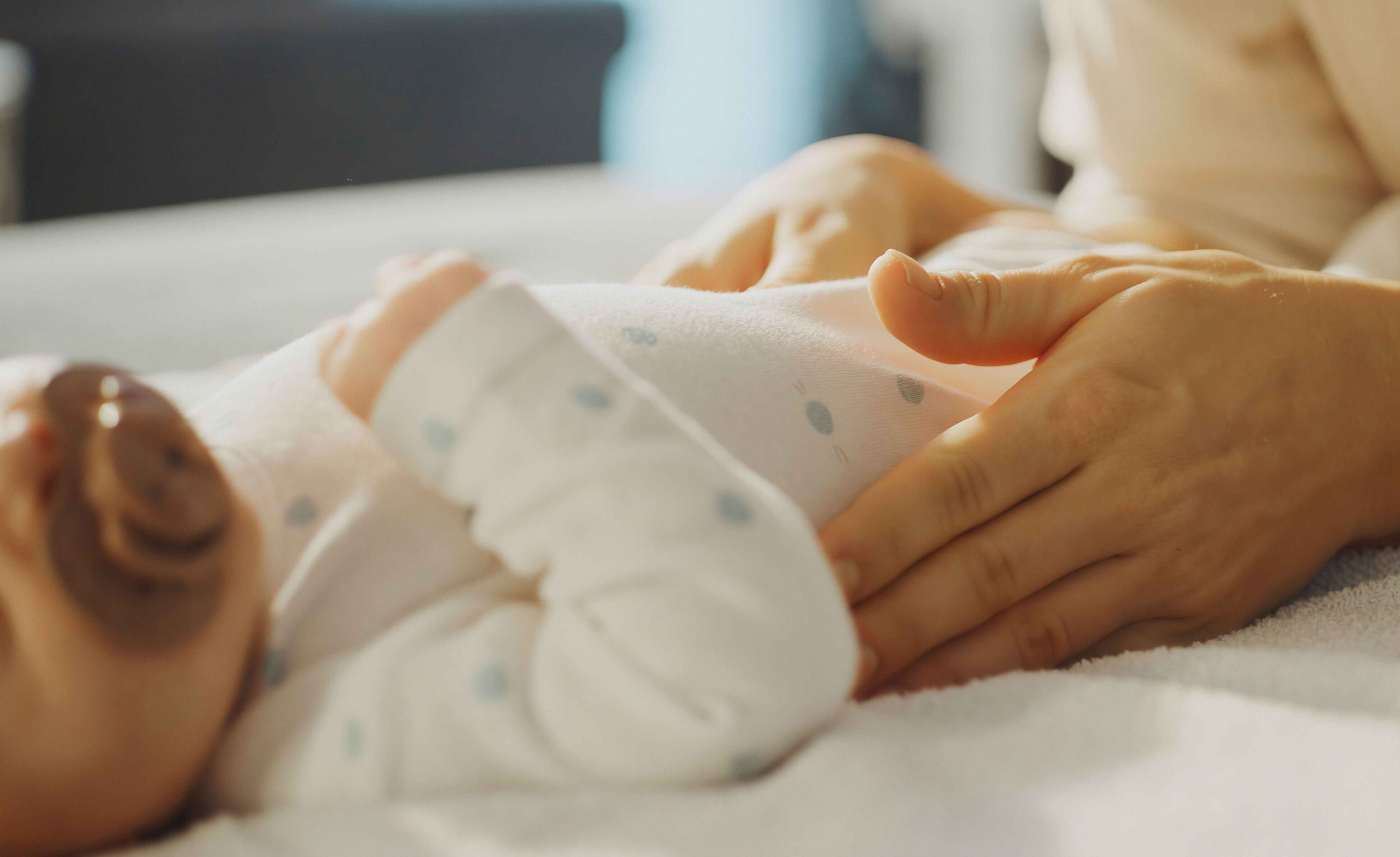 Auf einem Wickeltisch streichelt eine Mutter ihr kleines Baby.