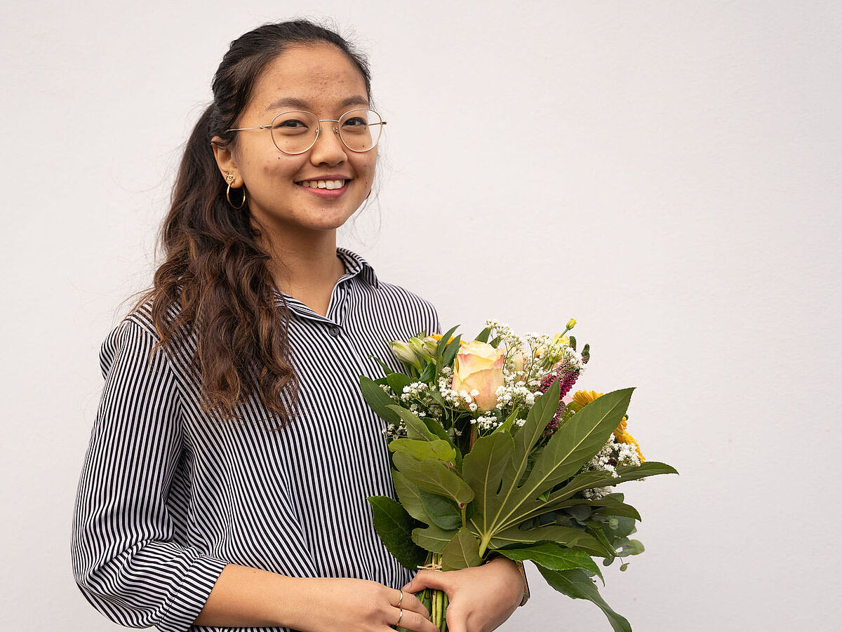Portrait der DAAD-Preisträgerin 2022, Adventina Padmyastuti mit einem Blumenstrauß in der Hand.