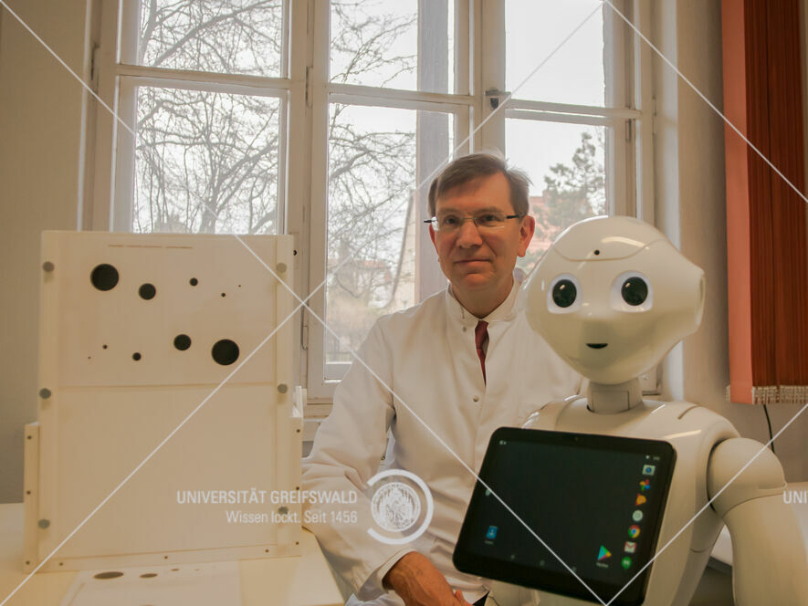 Prof. Dr. Thomas Platz und ein humanoider Roboter.