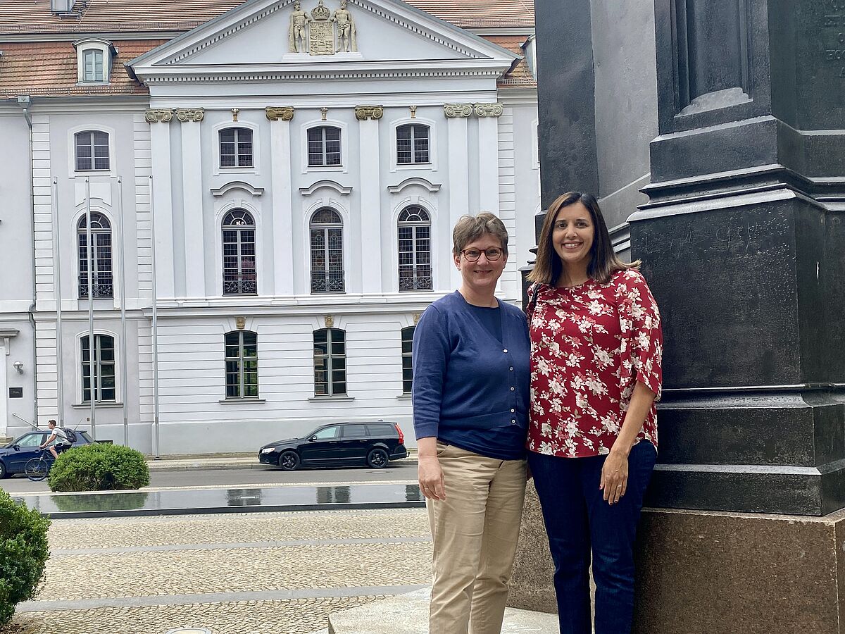 Foto von Annette Ehmler und Dr. Sapna Thwaite vor dem Universitätsgebäude in Greifswald.
