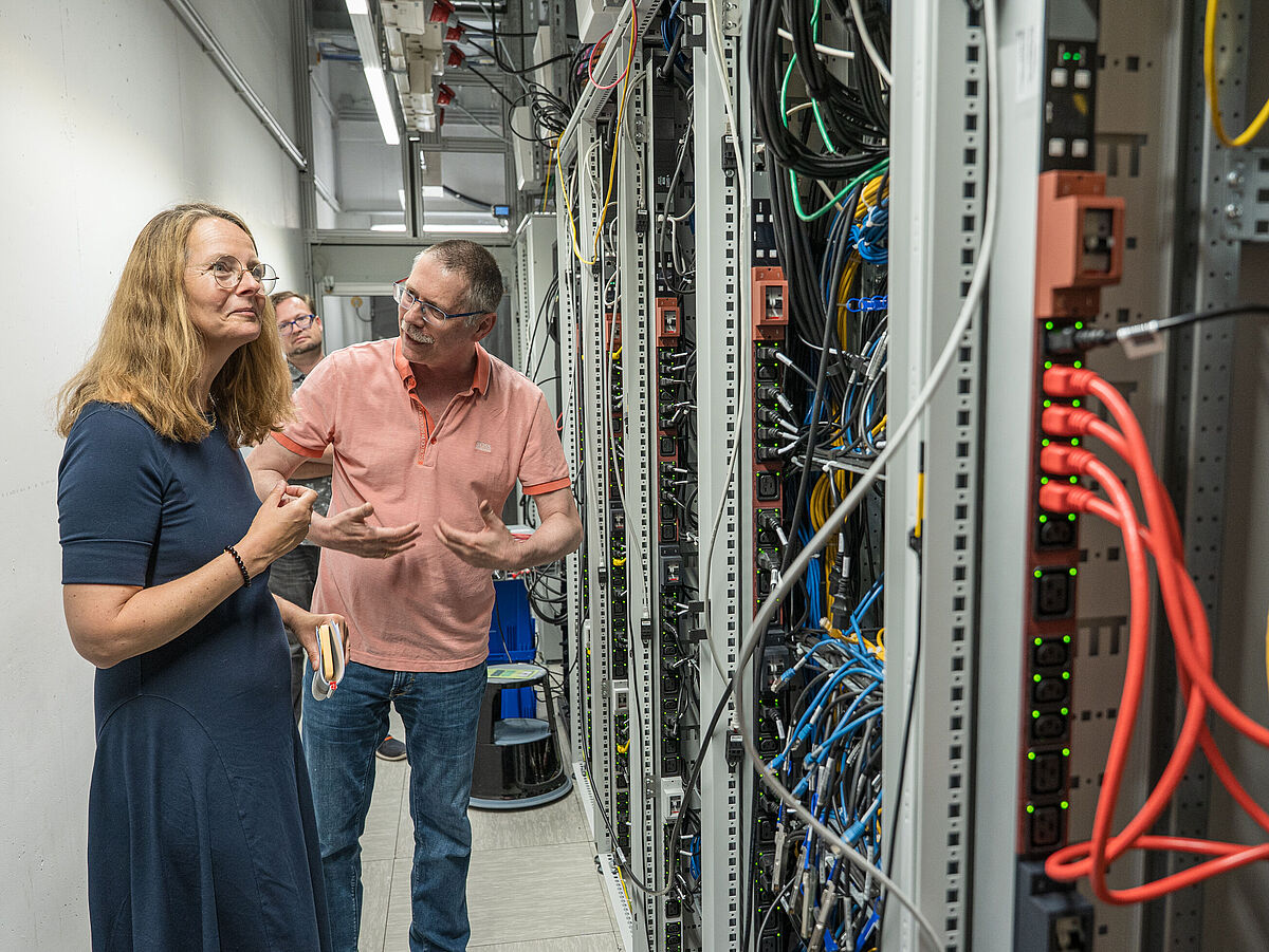 Eine Frau und ein mann stehen vor viel Technik im Rechenzentrum.