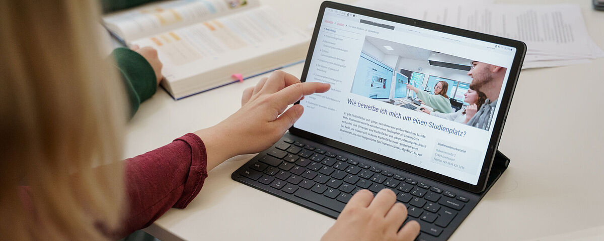 Eine Person zeigt auf ihren Laptopmonitor.