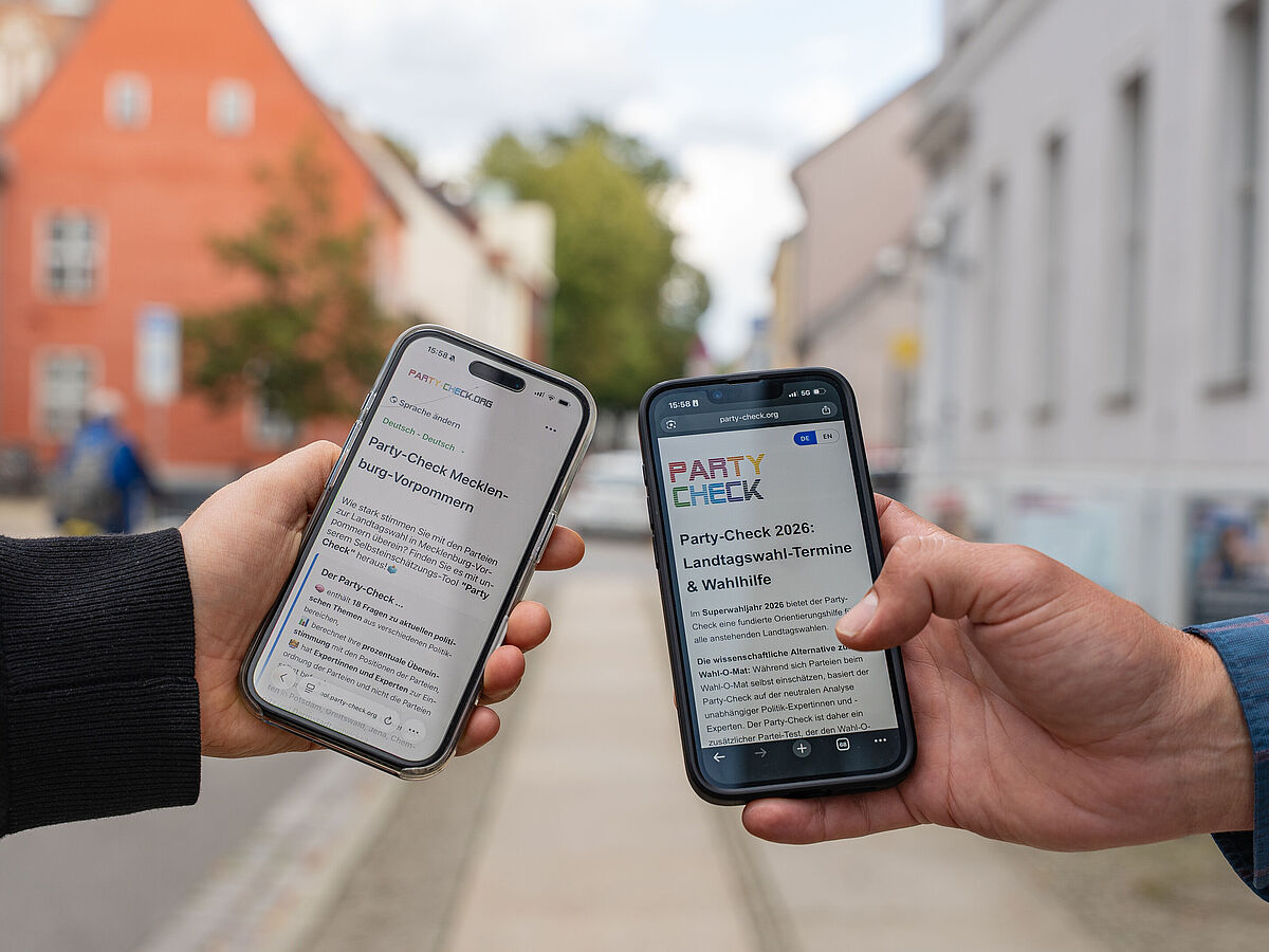 Die Onlinewahlhilfe-App auf dem Smartphone. Zu sehen sind jeweils eine Hand zweier Personen, die Smartphones halten.