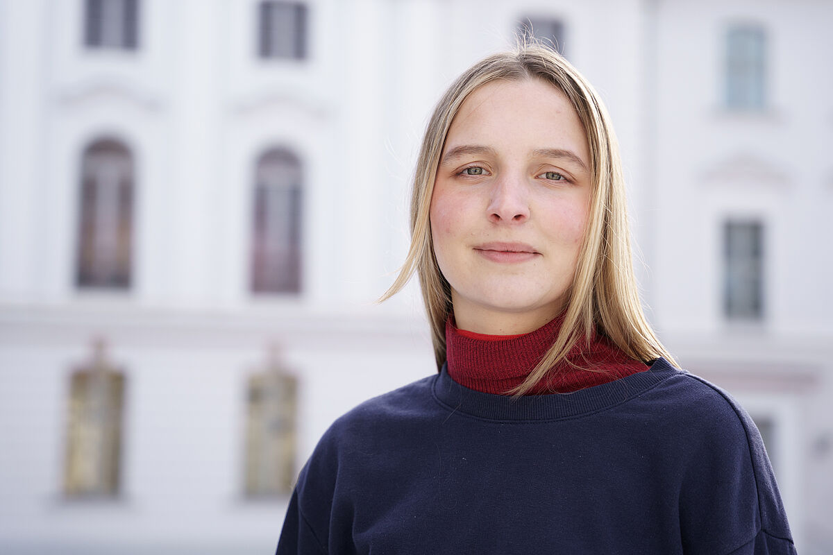 Ein Porträt von Mathilda König vor dem Universitätshauptgebäude.