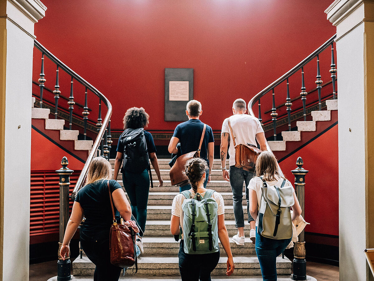 Studierende sitzen auf einer Treppe im Alten Audimax der Uni Greifswald.