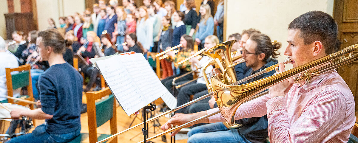 The image shows men with brass instruments sat in front of the choir.