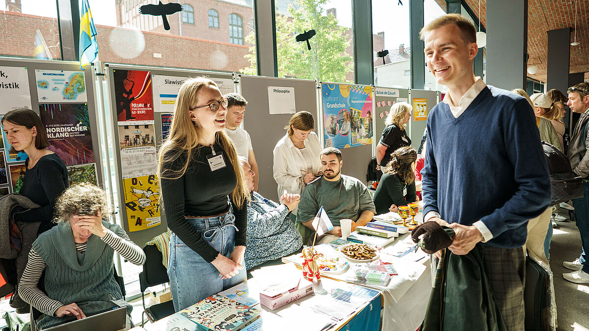 Auf dem Infomarkt an den Hochschulinfotagen unterhalten sich Personen und die lachen auf dem Bild.
