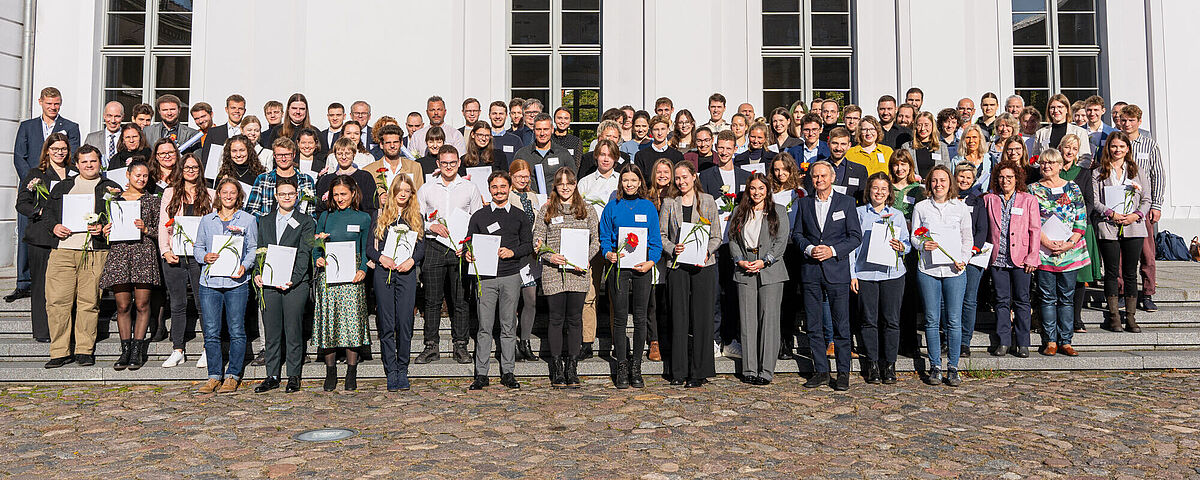 Group photo after the Deutschlandstipendium award ceremony 2023. The scholarship holders alonside their donors in front of the university's Main Building.