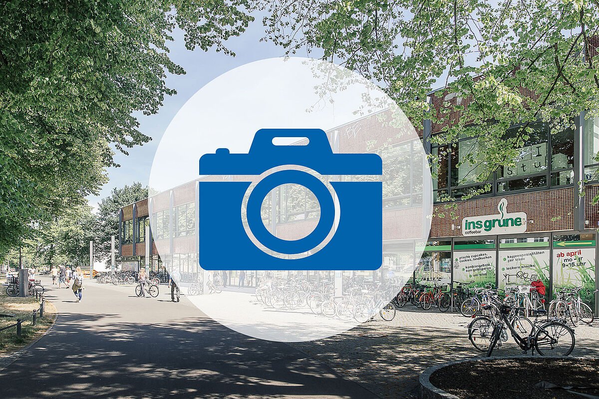 The Old Mensa in Greifswald can be seen, as well as trees in the background, and a camera symbol is depicted in the centre of the image.