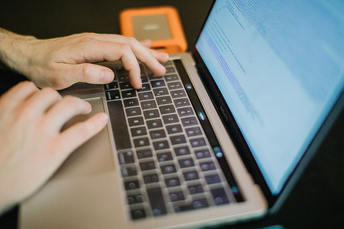 Zwei Hände geben Daten auf einer Notebook-Tastatur ein.