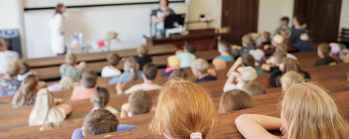 Kinder- und JugendUNI 2026 Kinder in einem alten Hörsaal hören einem Vortrag zu