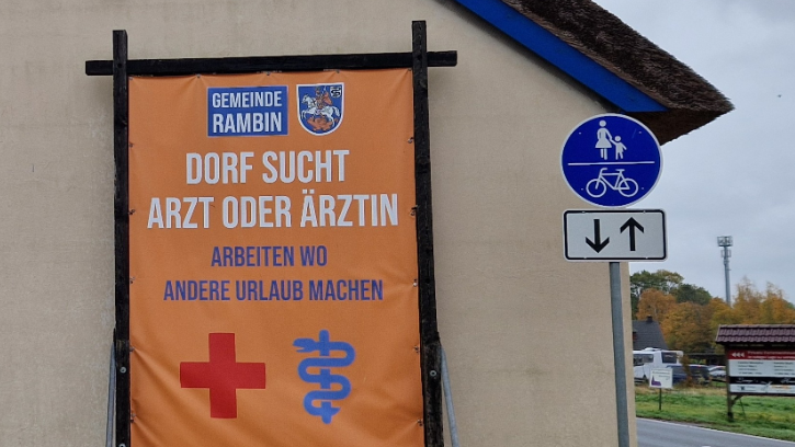 Ein Plakat vor einem Haus wirbt um Ärzte.