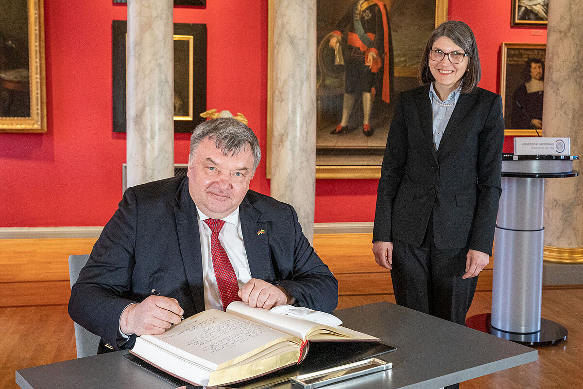 The Ambassador of Lithuania signing the university's guest book in the university's Aula.