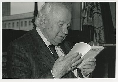 Schwarzweiß-Porträt von Wolfgang Koeppen. Er liest in einem Buch.