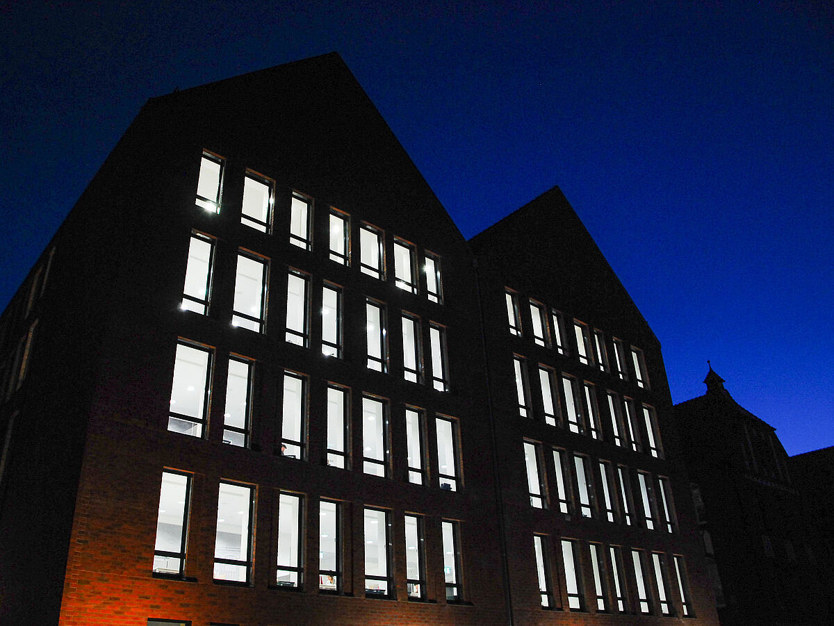 In der Dunkelheit sind die durch LED-Lichter beleuchteten Fenster der Bereichsbibliothek zu sehen.