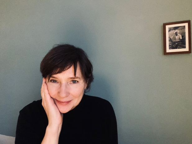 Annette Schuhmann lächelt freundlich in die Kamera. Sie sitzt vor einer grauen Wand.