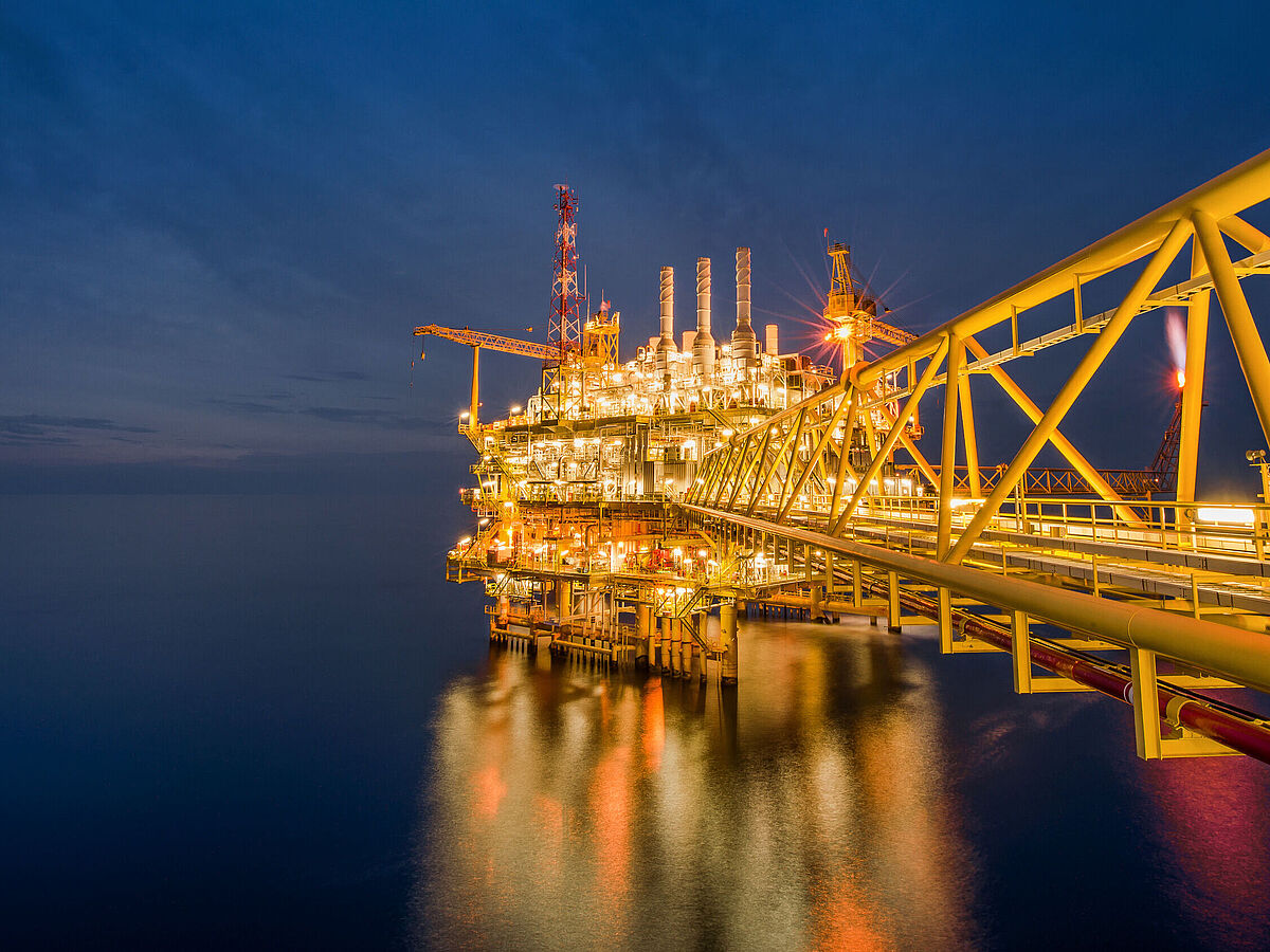 Eine industrielle Offshore-Öl- und Gasbohrplattform bei Nacht im Golf von Thailand.