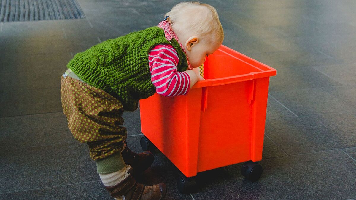 Ein kleines Kind schaut in eine Spielzeugkiste.