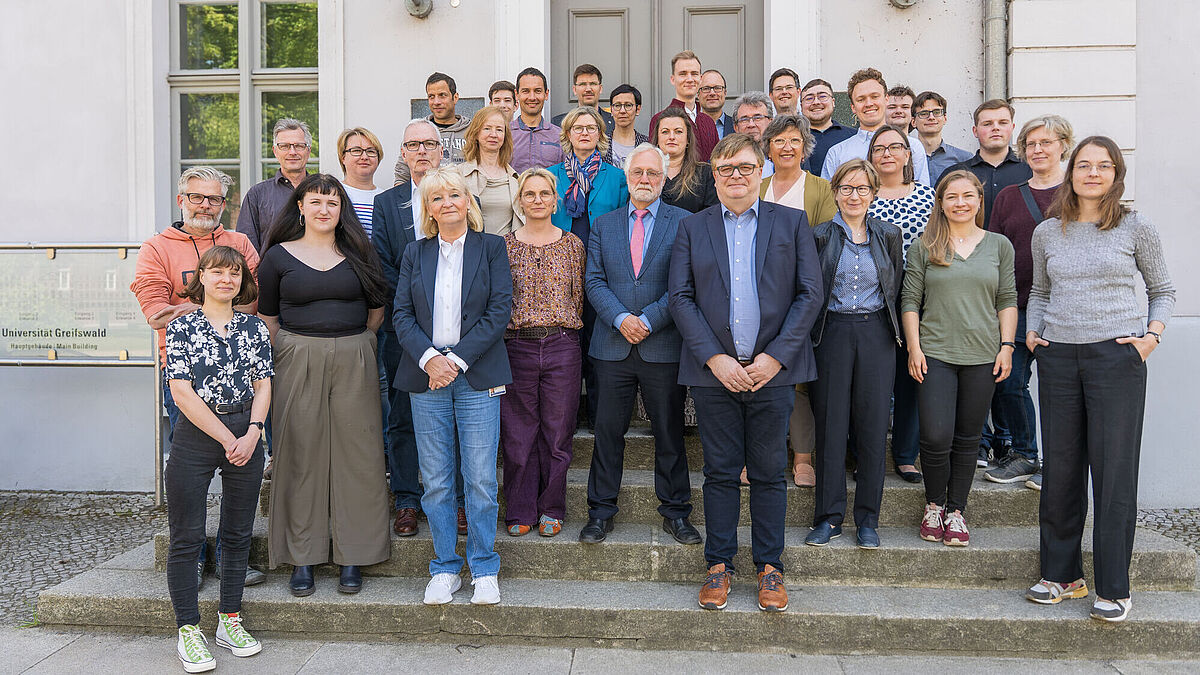 Auf dem Bild ist der Senat in seiner Zusammensetzung im Mai 2025 zu sehen. Die Gruppe steht auf der Treppe vor dem Hauptgebäude der Universität. 