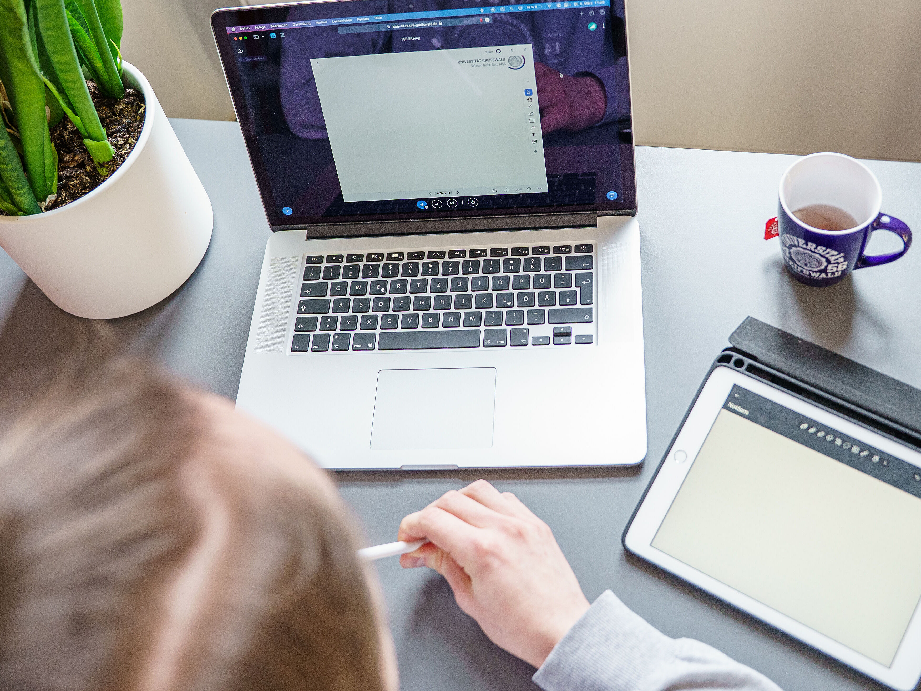Symbolbild Online-Sitzung Eine Person sitzt vor einem geöffneten Laptop in einem Online-Meeting.